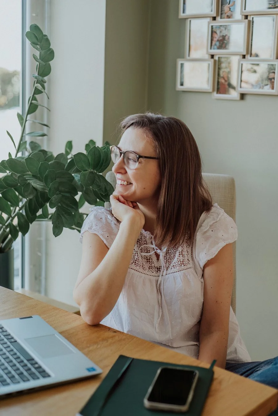 Little Green Gem Marketing. She is sitting at her desk with her laptop open and notebook out.