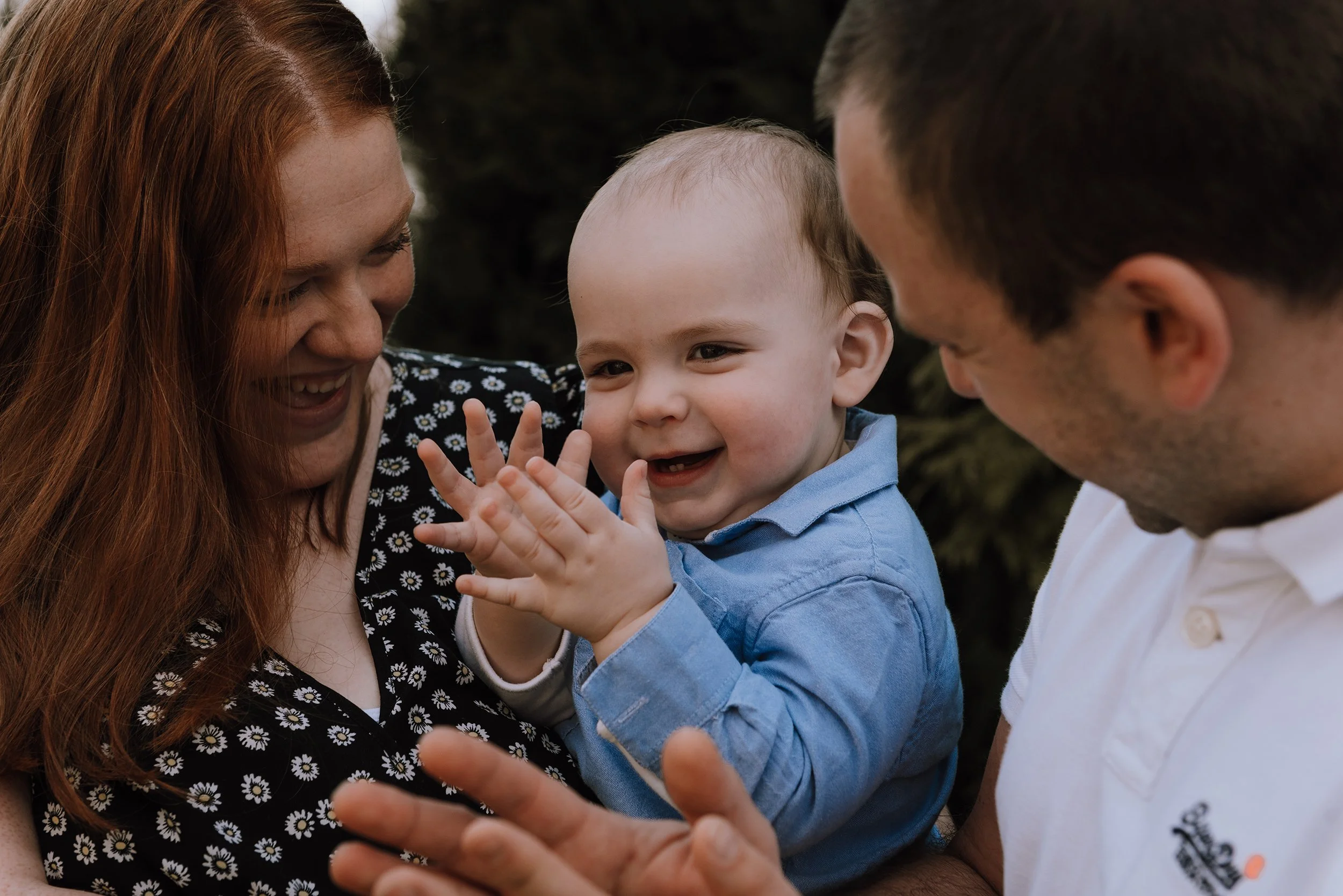 Mum and dad smiling and clapping with toddler