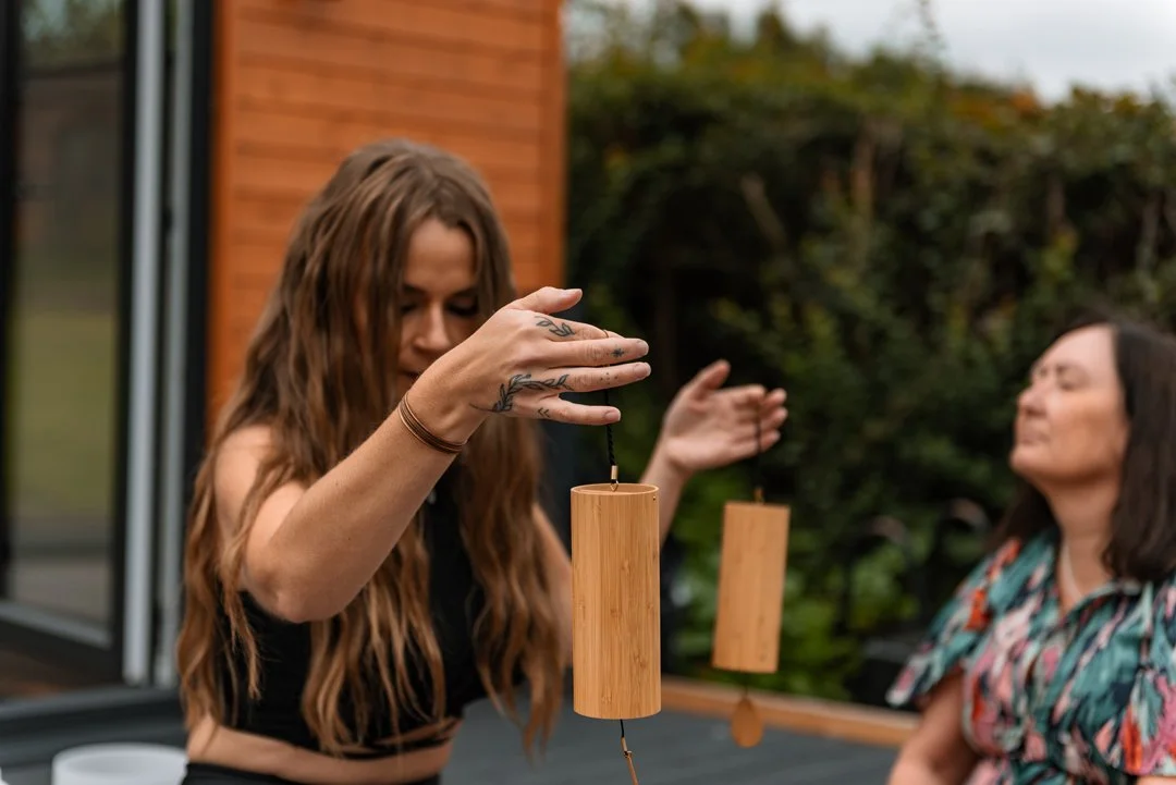 Holly Hollins, Higher Frequency coach, she is holding up instruments for an outdoor sound bath meditation.