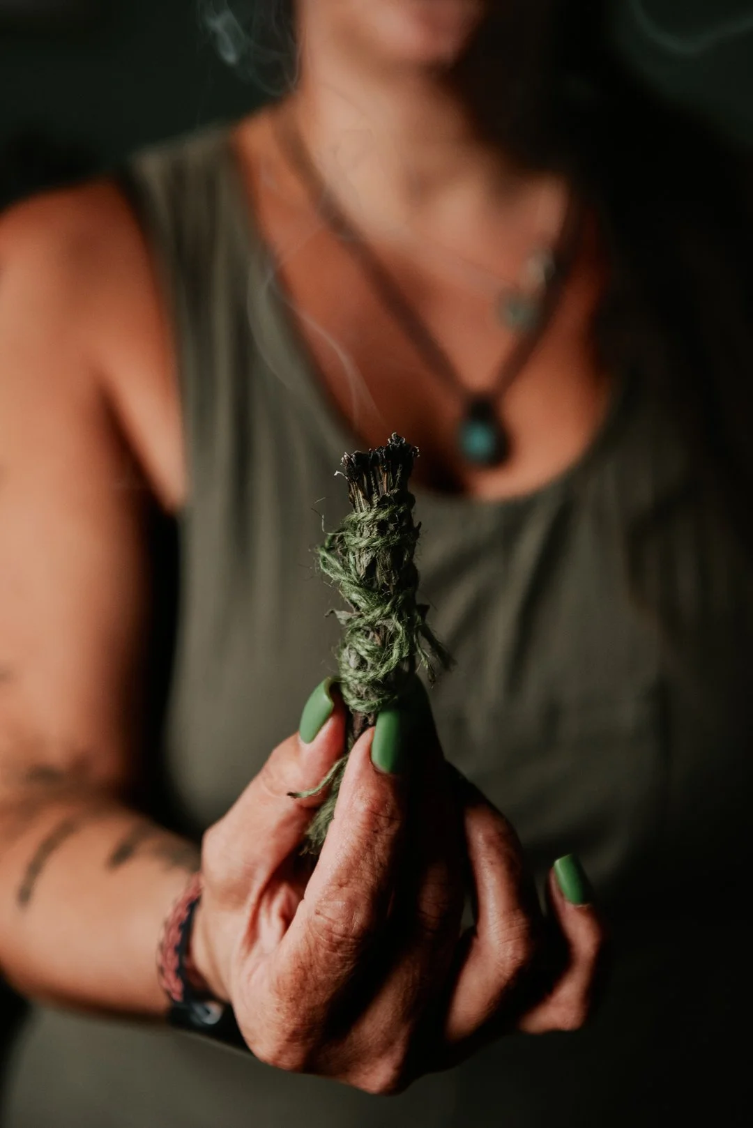 Alternative Advocacy. Abi is holing out a bundle of cleansing herbs which is gently releasing smoke into the room.