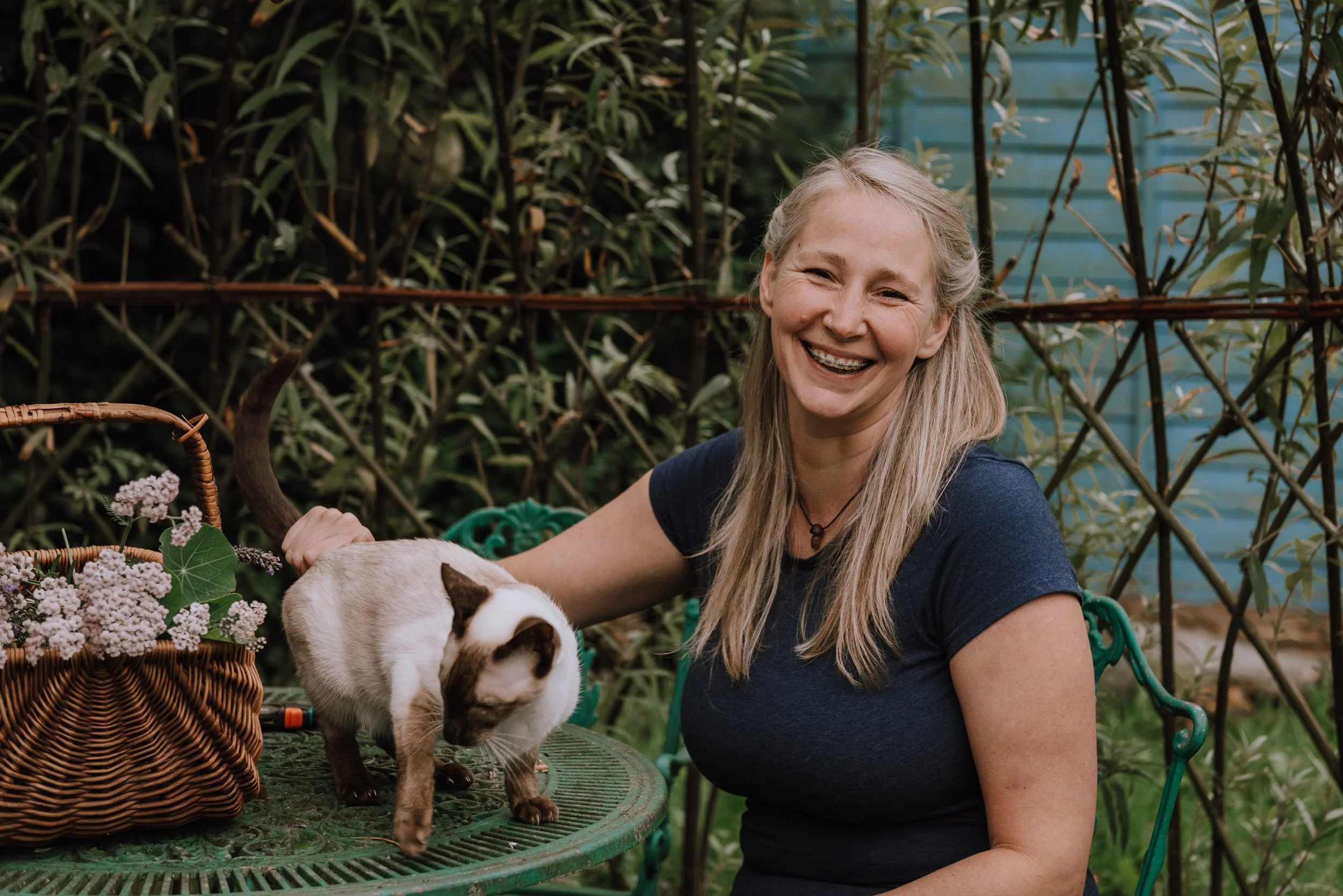 Woman smiling in her garden while stroking a beautiful cat.