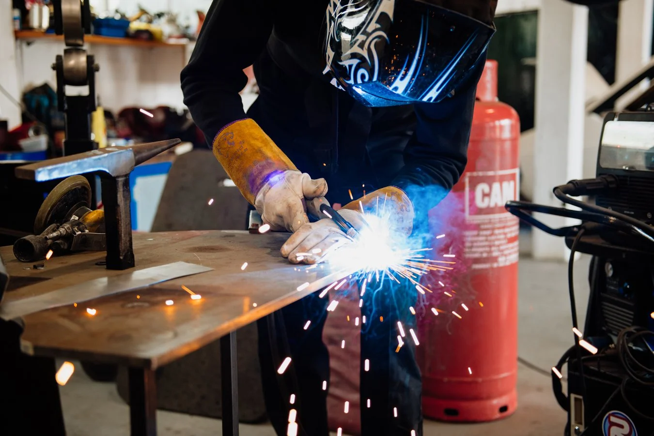 Man wekding metal pieces in a commercial car services garage. Hot sparks are flying