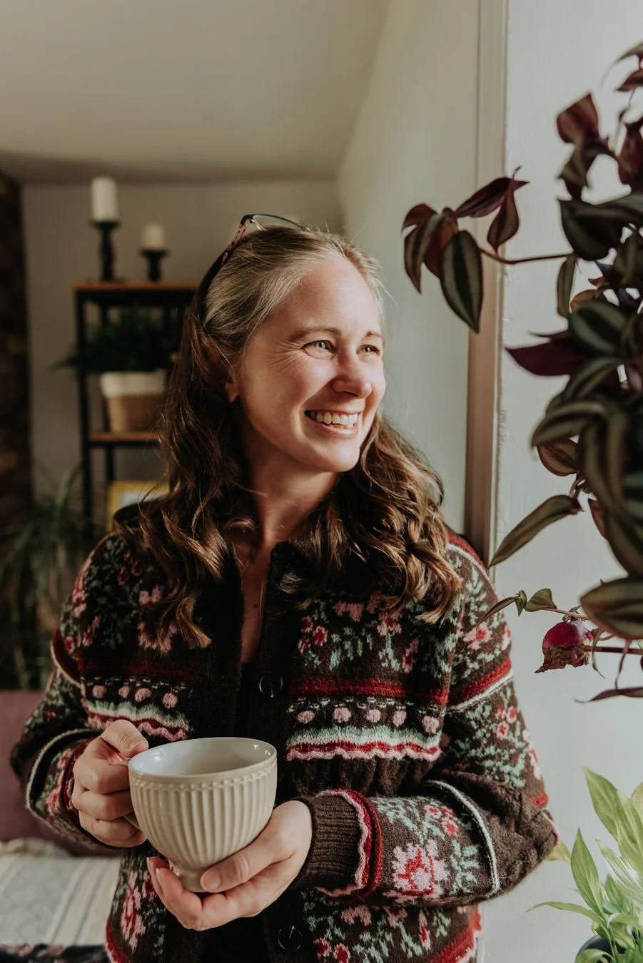 Jen, The Therapy Nook. Jen is smiling while looking out of her window. She's holding a big mug of herbal tea and looks very relaxed.