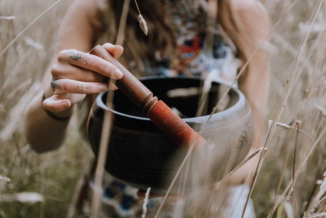 An image of a Tibetan Singing bowl being played. The bowl is held up to the camera.