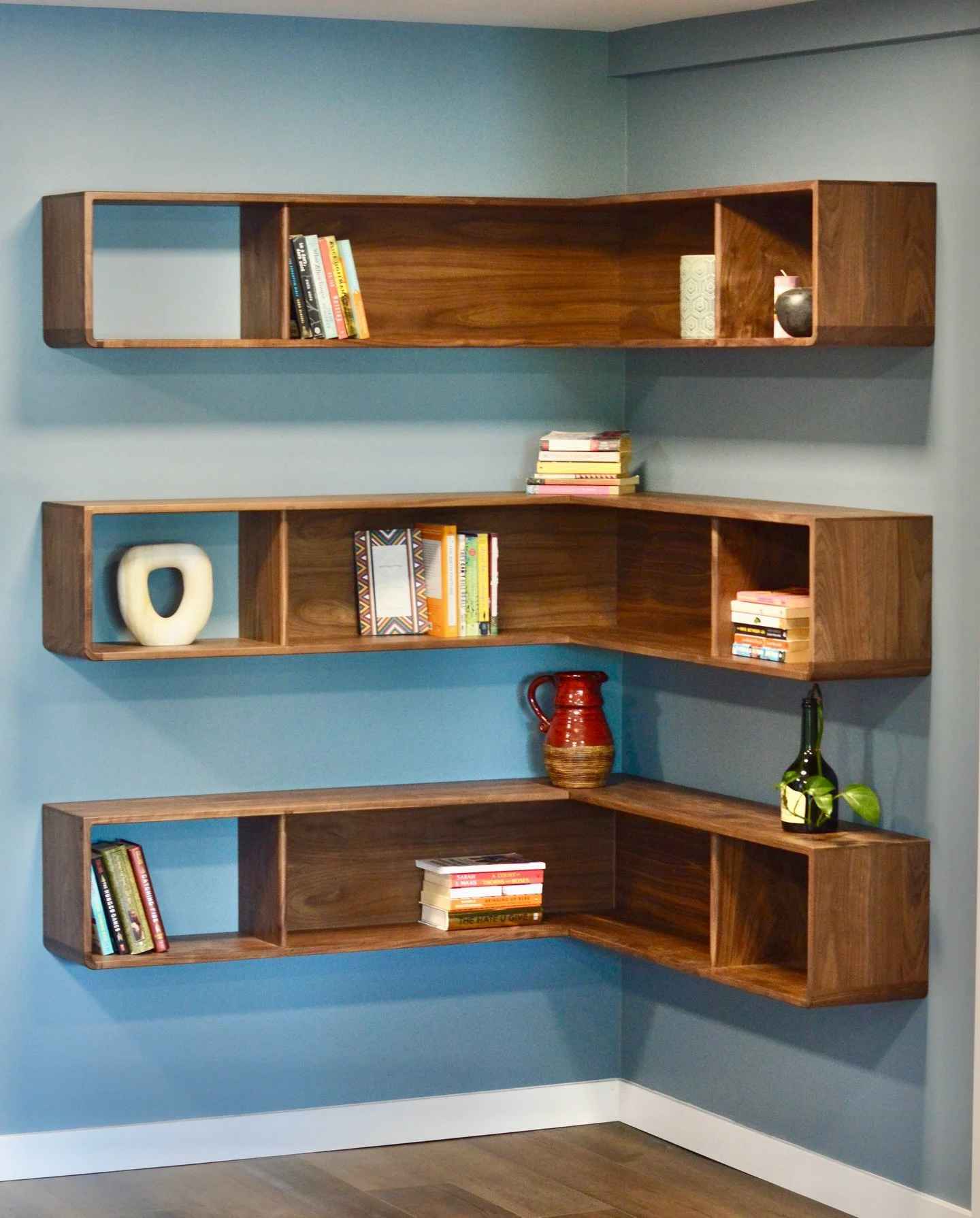 Think outside the built in!

There&rsquo;s more to life than filling every wall with floor to ceiling cabinets. This design was intended to add plenty of open storage without making the space feel too small. 

Add in some rounded corners and open bac