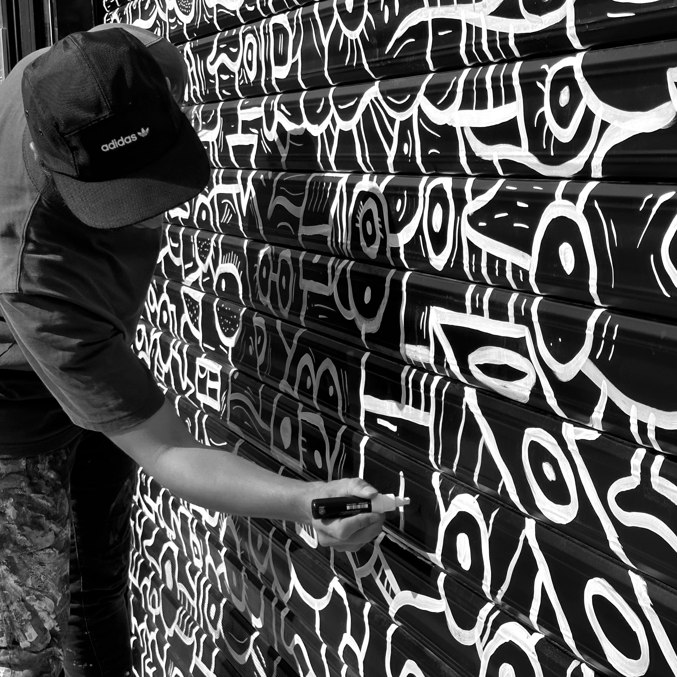 L'artiste français Jigé à Lille peinture street art en rue avec casquette noire Adidas