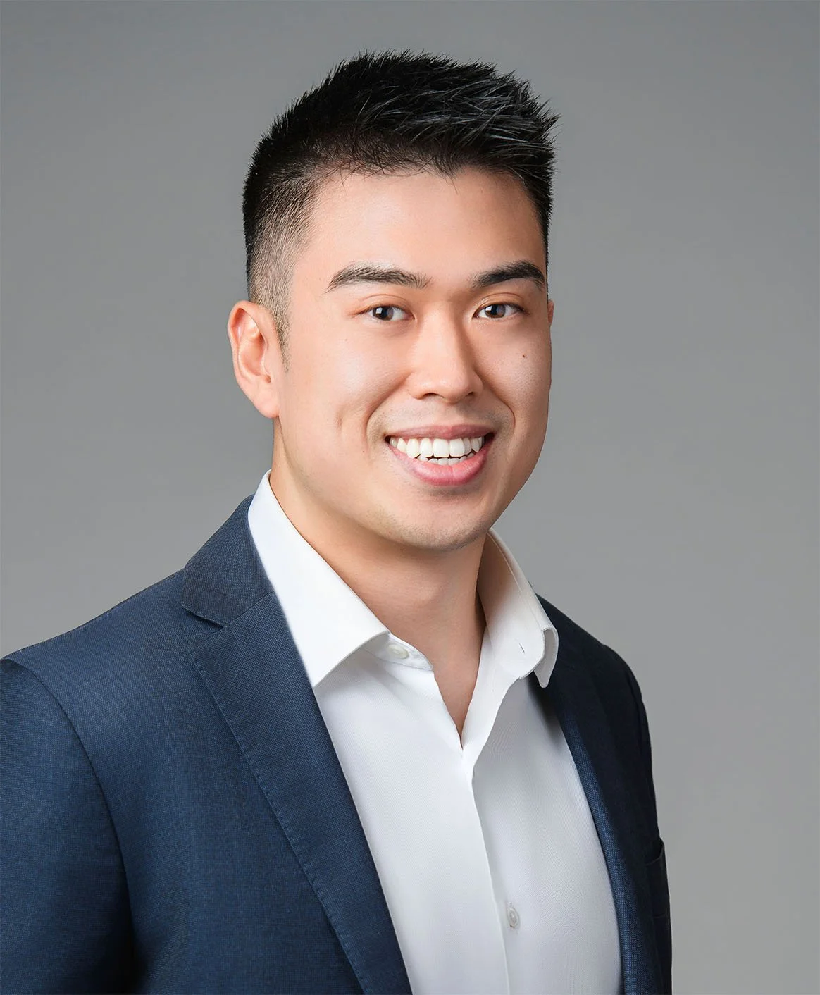 Desmond Tam
Senior Associate Professional headshot of a young Asian man wearing a dark suit, white shirt, and a striped tie, smiling at the camera against a light gray background.