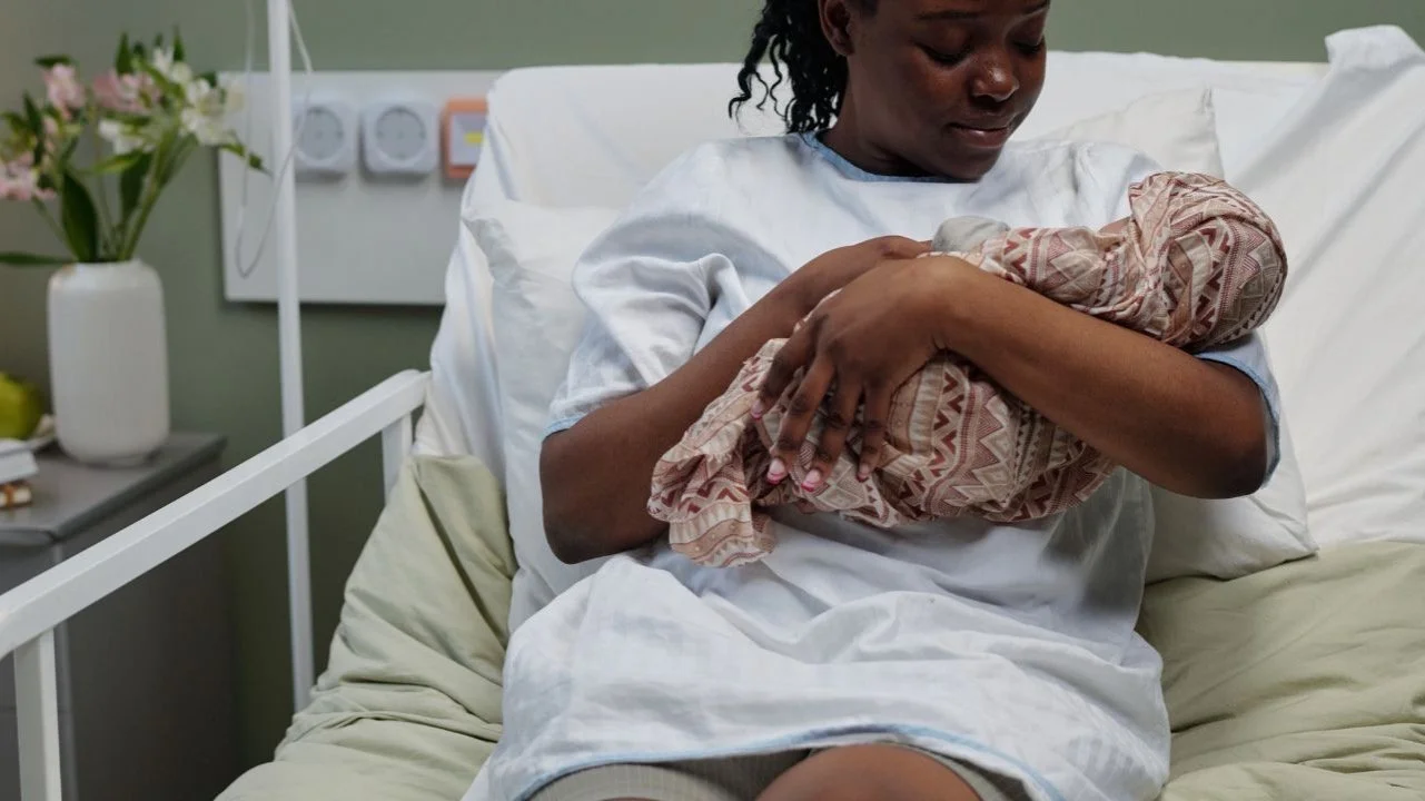 mom holding newborn baby in hospital bed