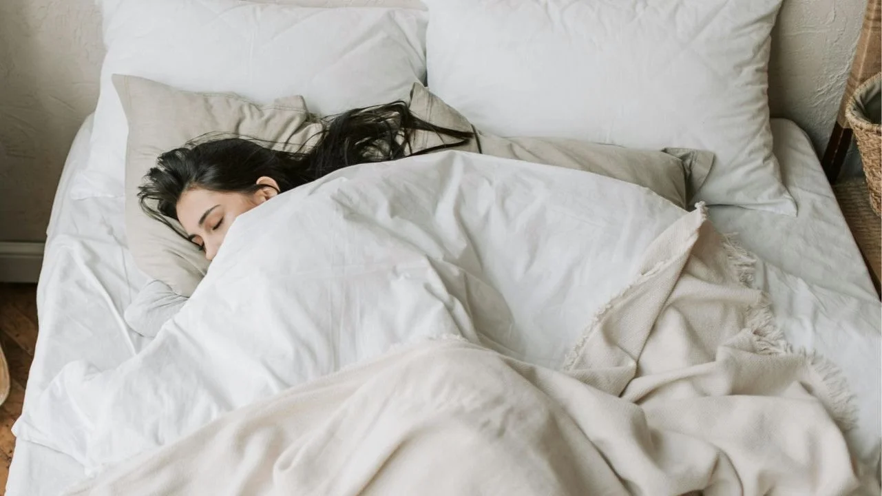 woman sleeping in bed under covers