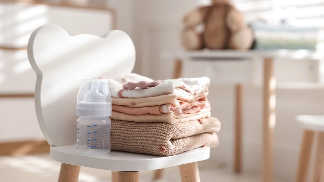 baby bottle and clothes on a chair in a nursery