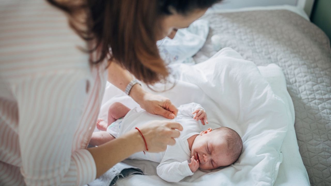 woman dressing her newborn baby