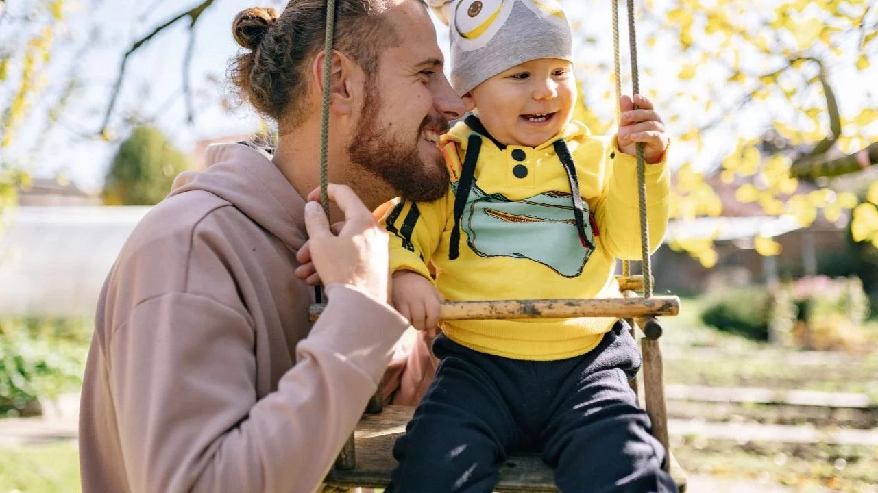 man with toddler on swing
