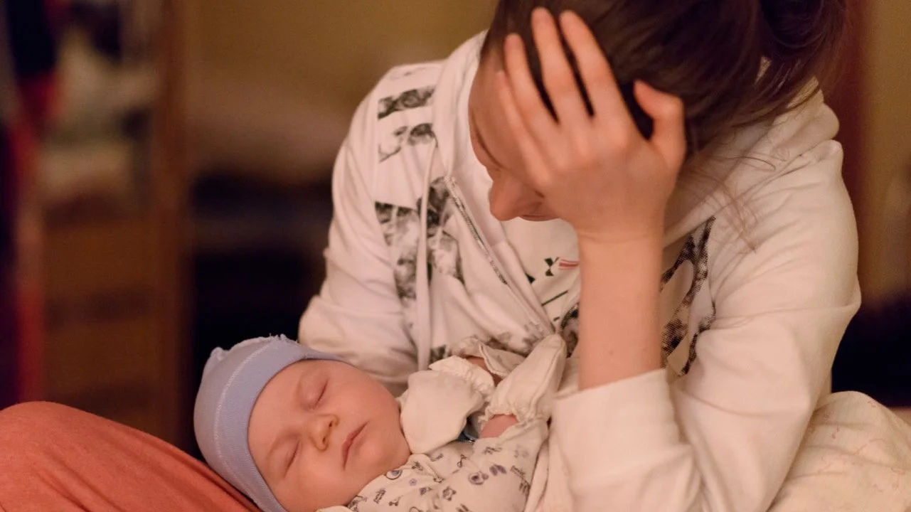 stressed mom holding sleeping baby