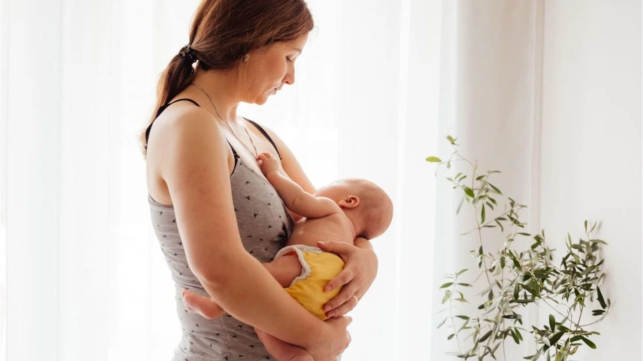 woman breastfeeding a baby standing up