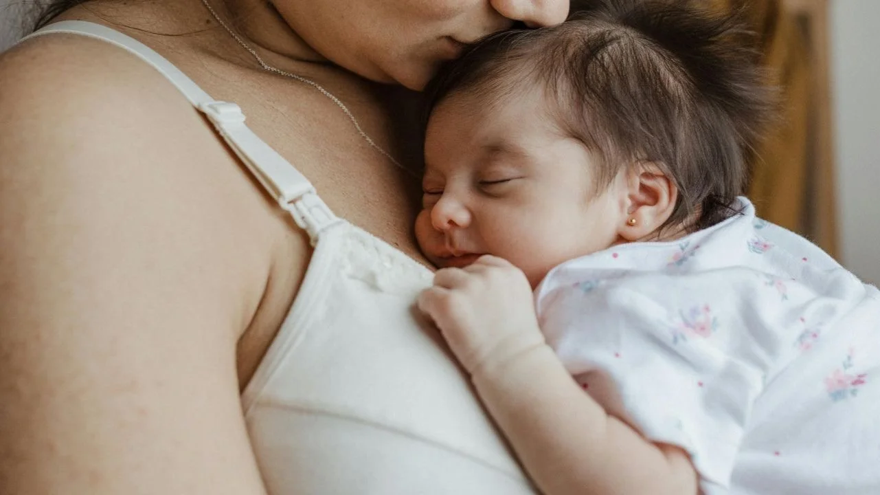 woman wearing a nursing bra holding her sleeping baby