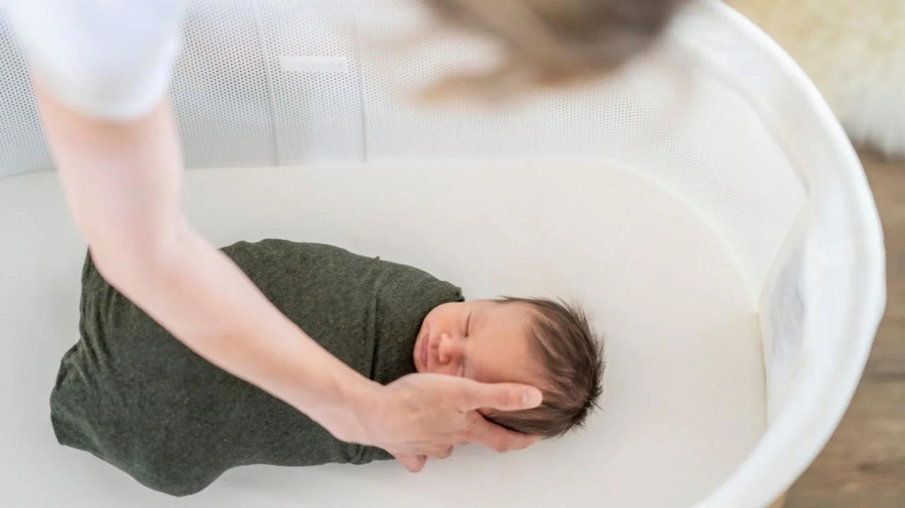 baby swaddled sleeping in bassinet