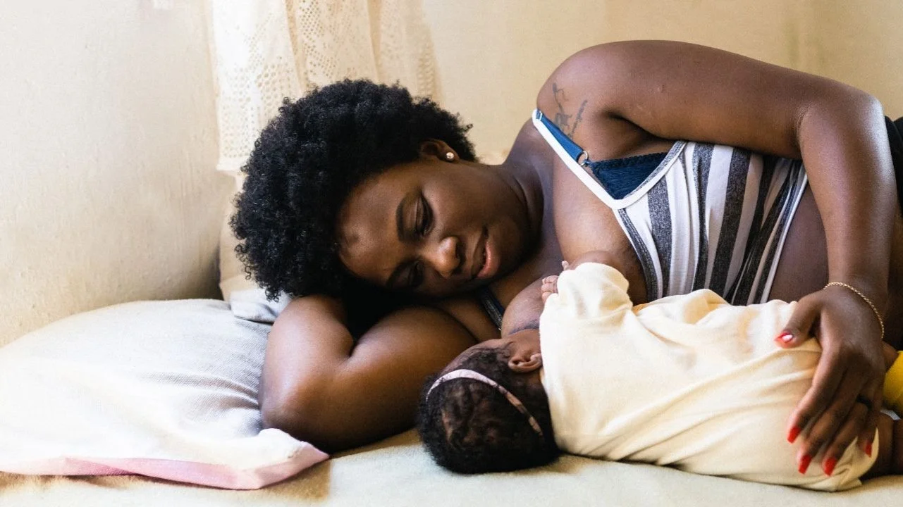 woman laying in bed nursing her baby
