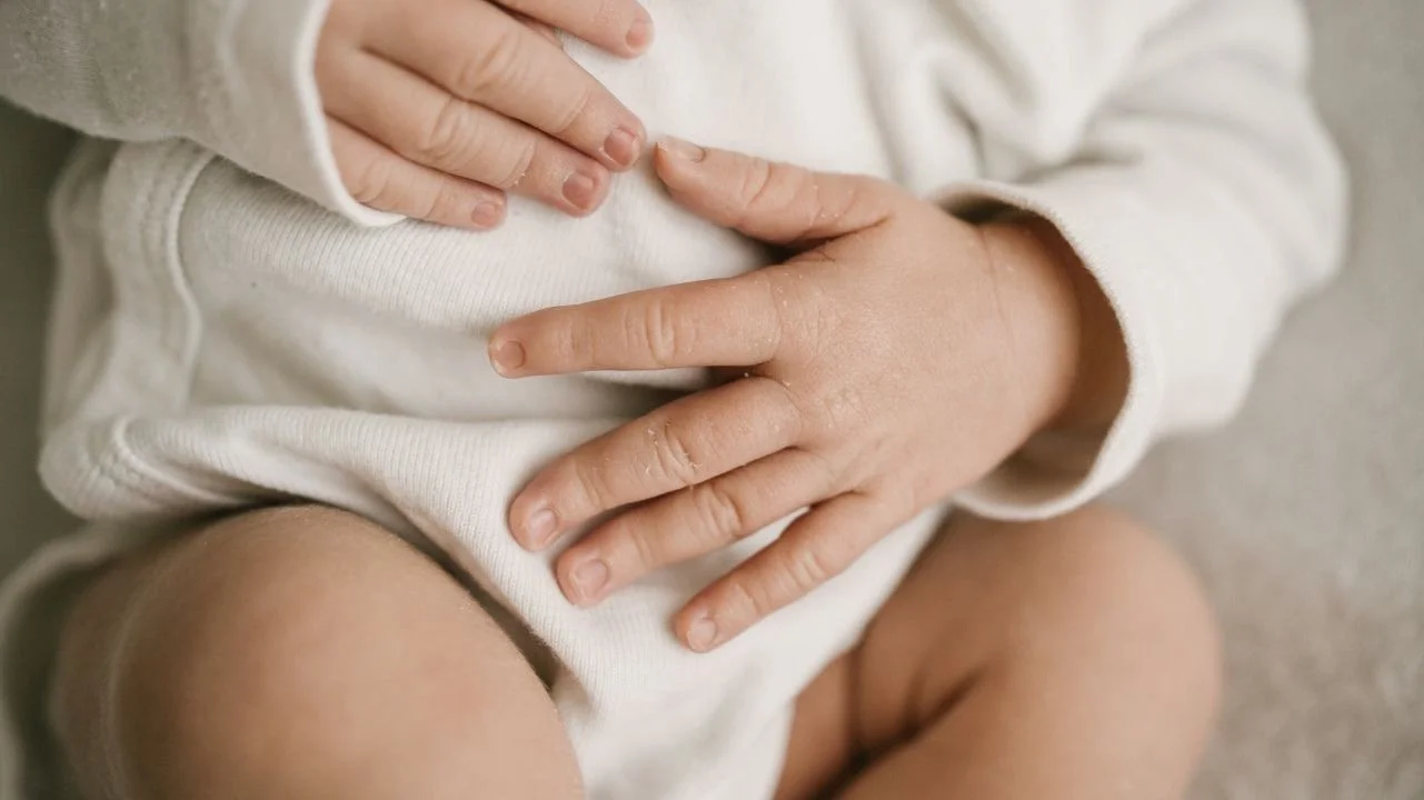 close up of baby's hands over their belly