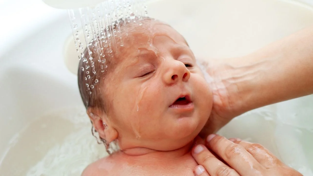newborn getting rinsed in a bath tub