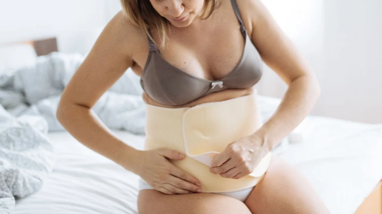 woman putting on abdominal support band in bed