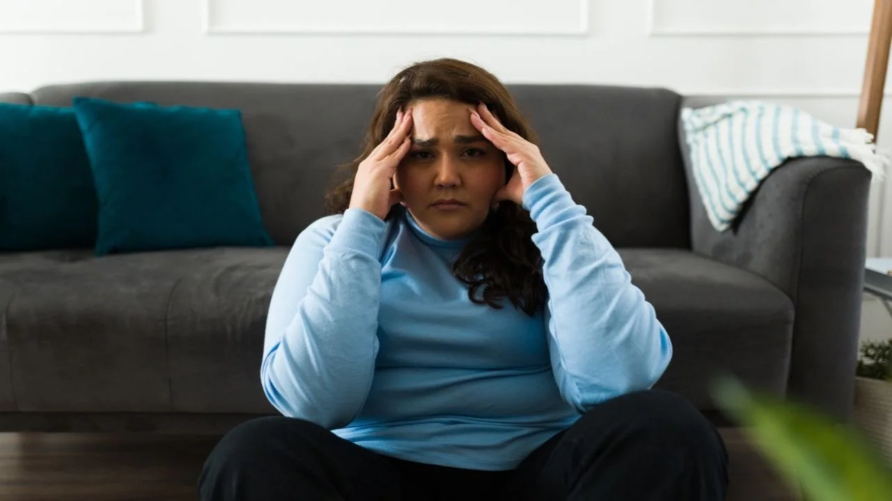 stressed woman sitting on floor in front of couch