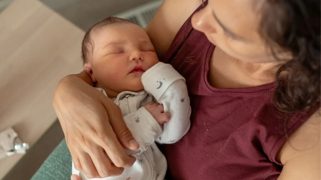 baby sleeping in mom's arms
