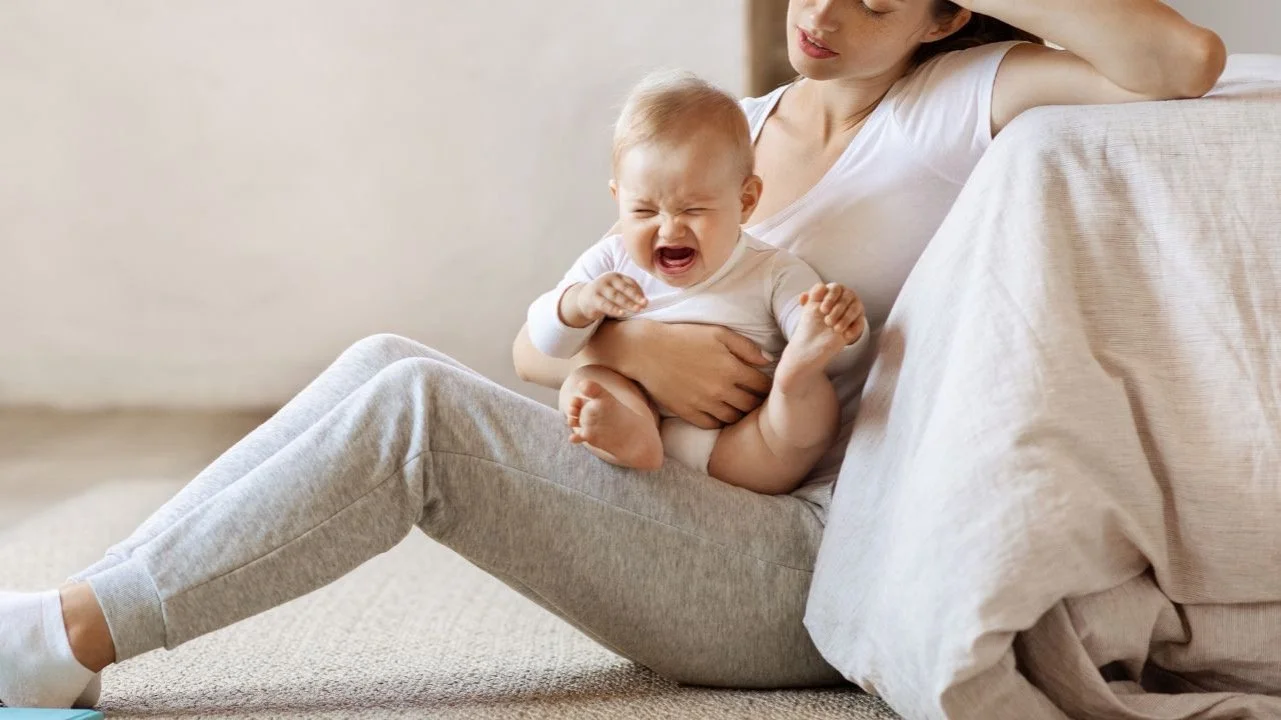 tired mom holding screaming baby