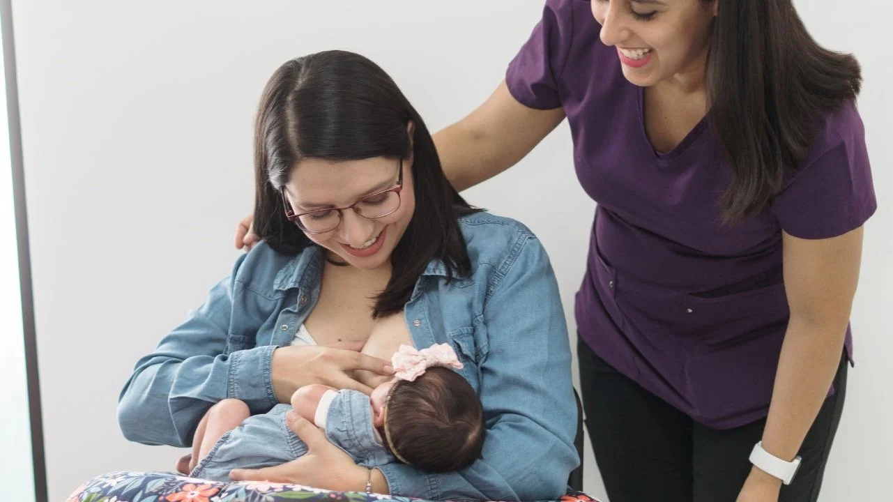 woman breastfeeding with assistance from lactation consultant