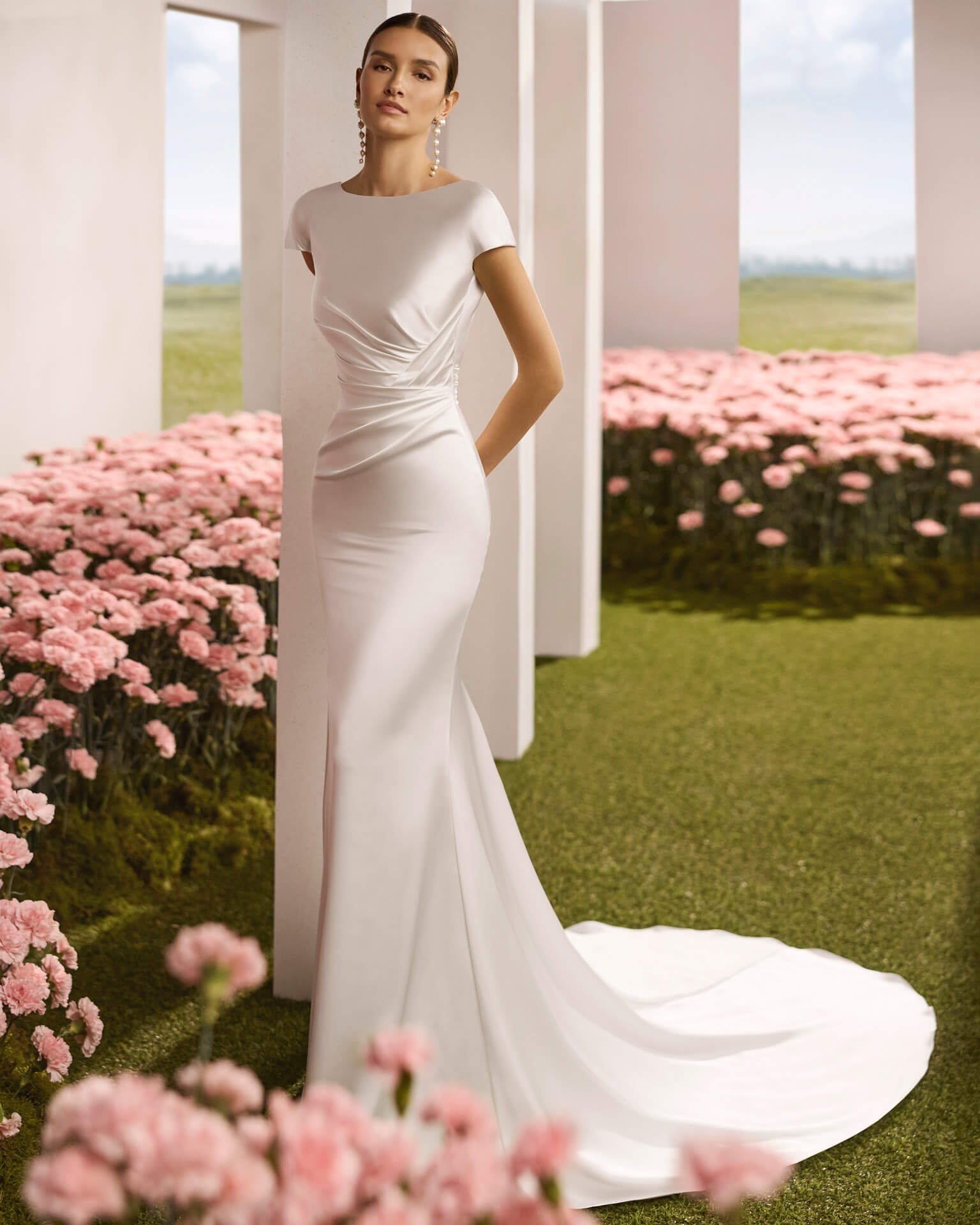 Bride wearing a Satin wedding Dress by Rosa Clara Couture in a hallway full of flowers at Ashley and Alexandrias Bridal Atelier Detroit Michigan