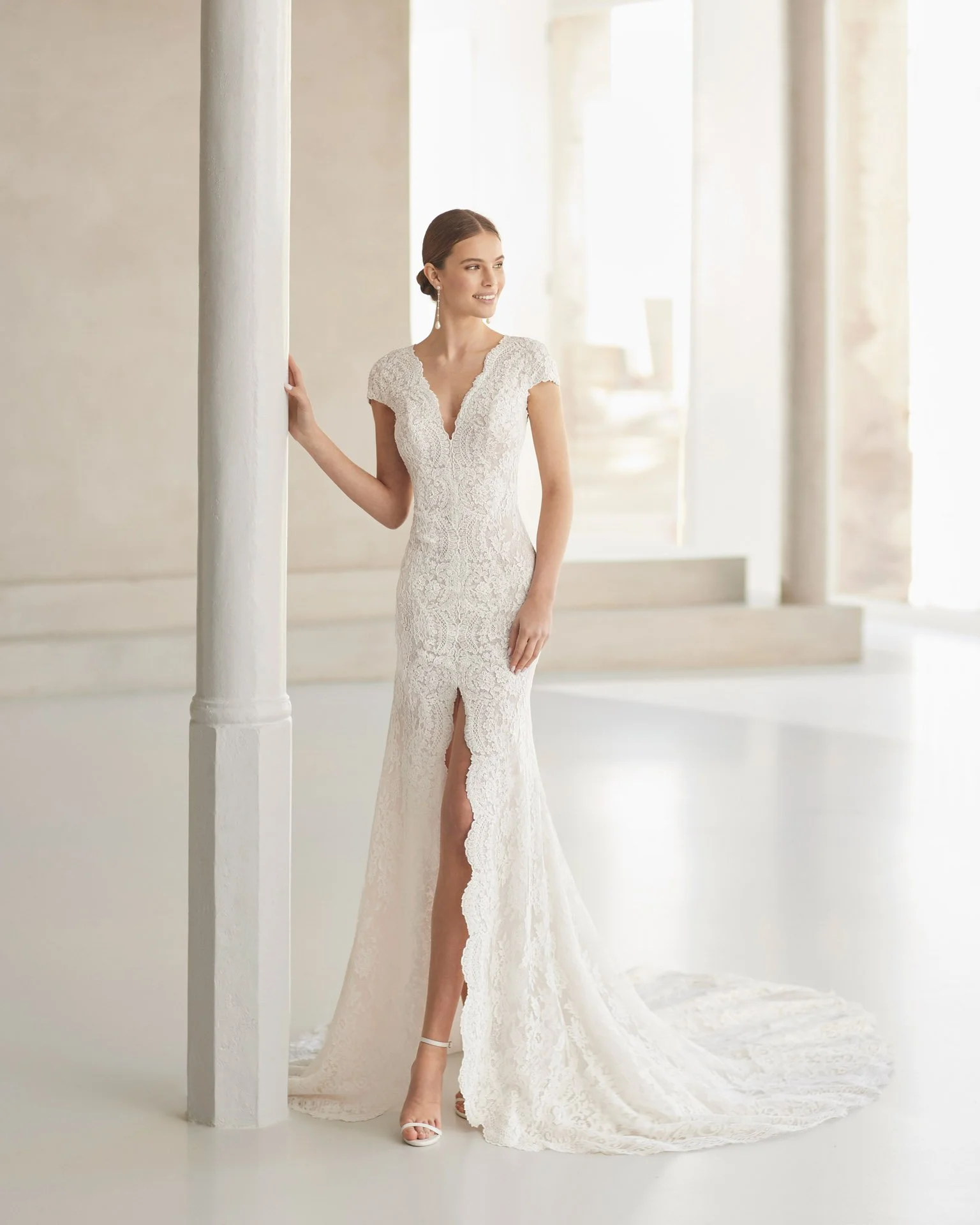 Rosa Clara Couture lace wedding dress with bride standing near column found at Ashley and Alexandrias Bridal Atelier Bloomfield Hills Michigan