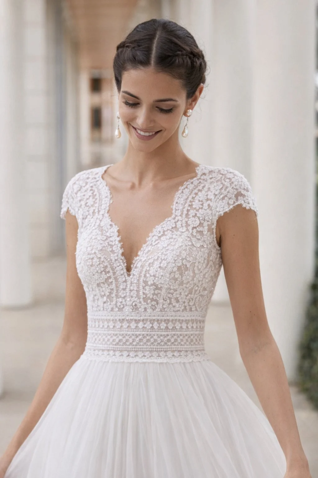 Bride wearing a Rosa Clara Couture Sauca Italian tulle and lace V-neck bodice near a column smiling broadly Ashley and Alexandrias Bridal Atelier/Boutique Detroit Michigan|