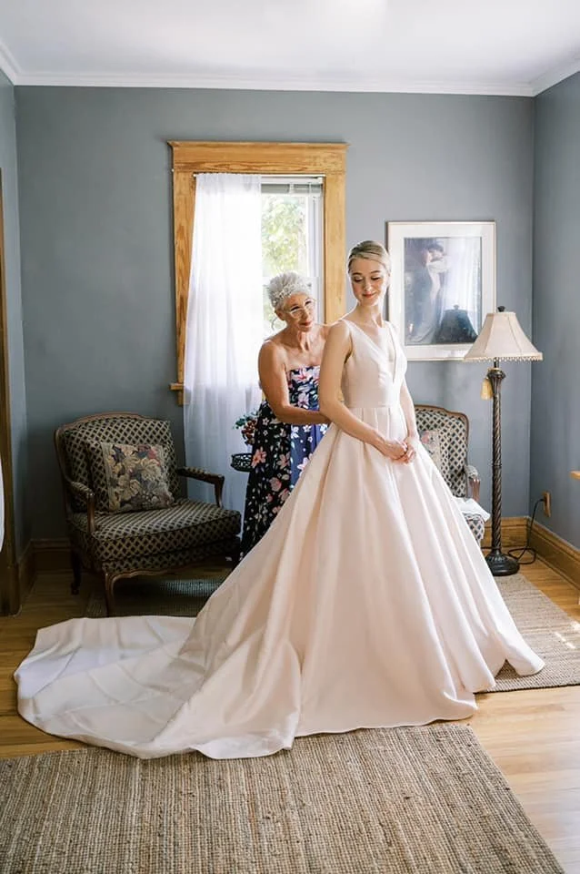 Mother embracing bride as she is preparing to become a wife in this beautiful Rosa Clara Couture Ballgown with V-neck and mikado look very happy for a garden wedding after visiting Ashley and Alexandrias Bridal Atelier in Southfield Michigan