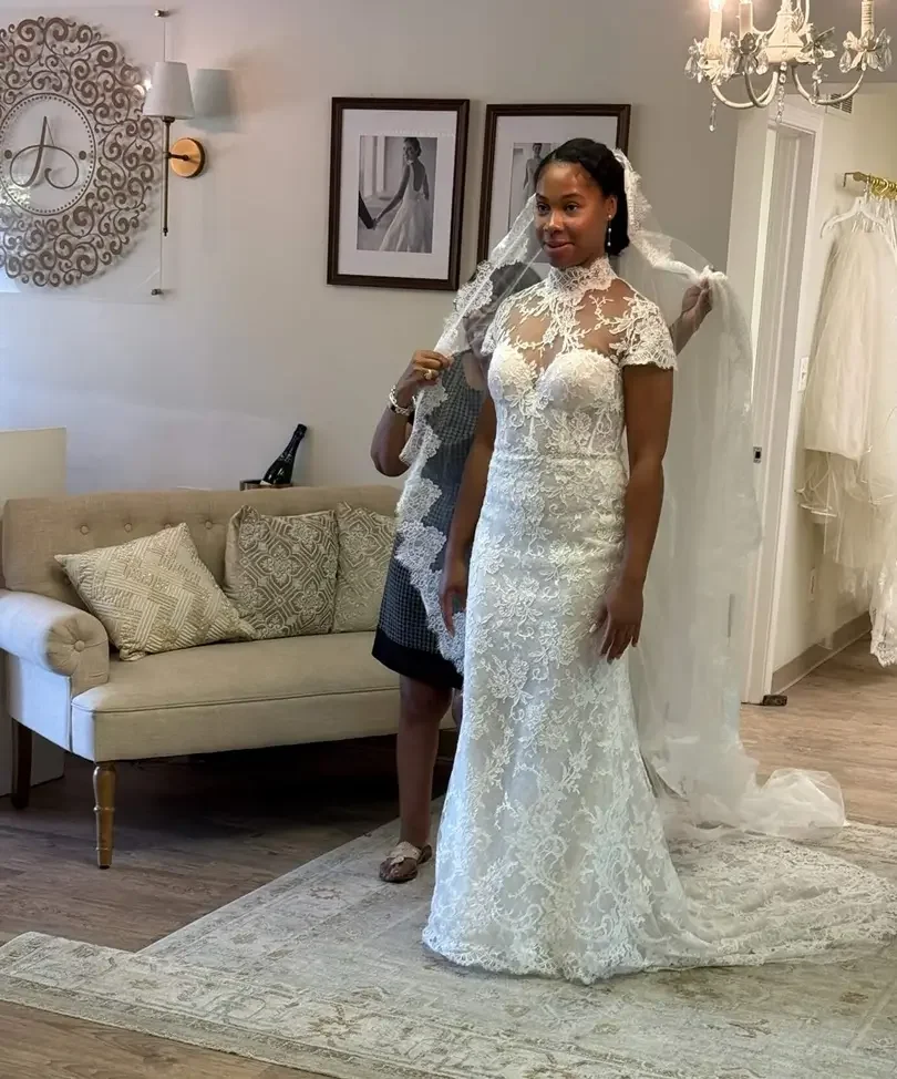 Bridal stylist helping a bride discover and try on a wedding dress from Rosa Clara Couture inside Ashley and Alexandrias Bridal Atelier Southfield Michigan