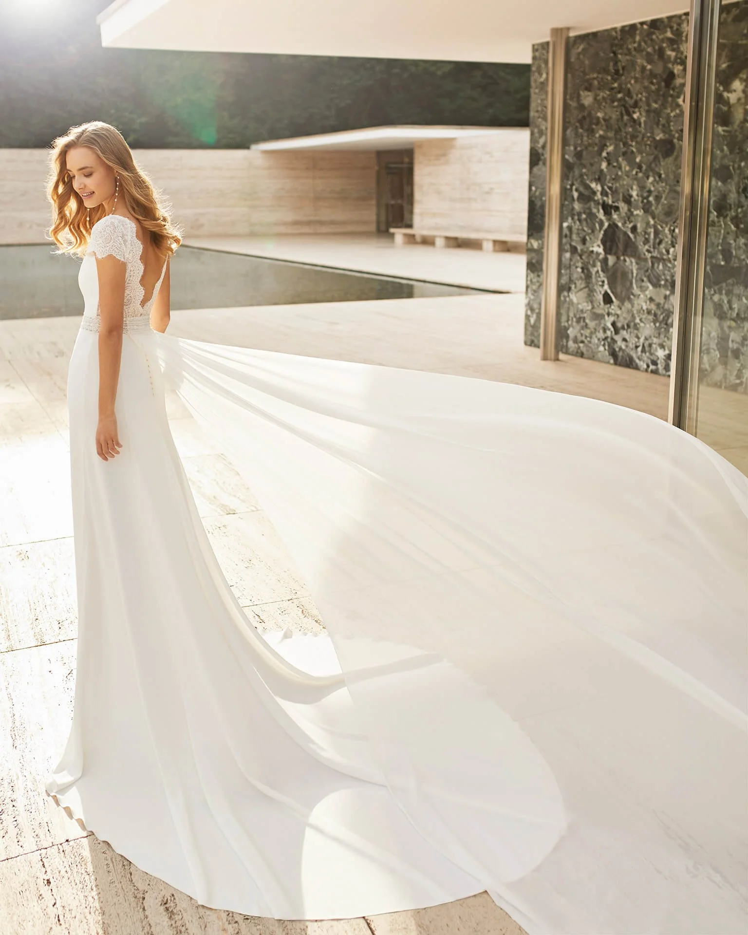 Bride near a pool wearing a crepe and lace wedding dress by Rosa Clara Couture at Ashley and Alexandrias Northville Michigan