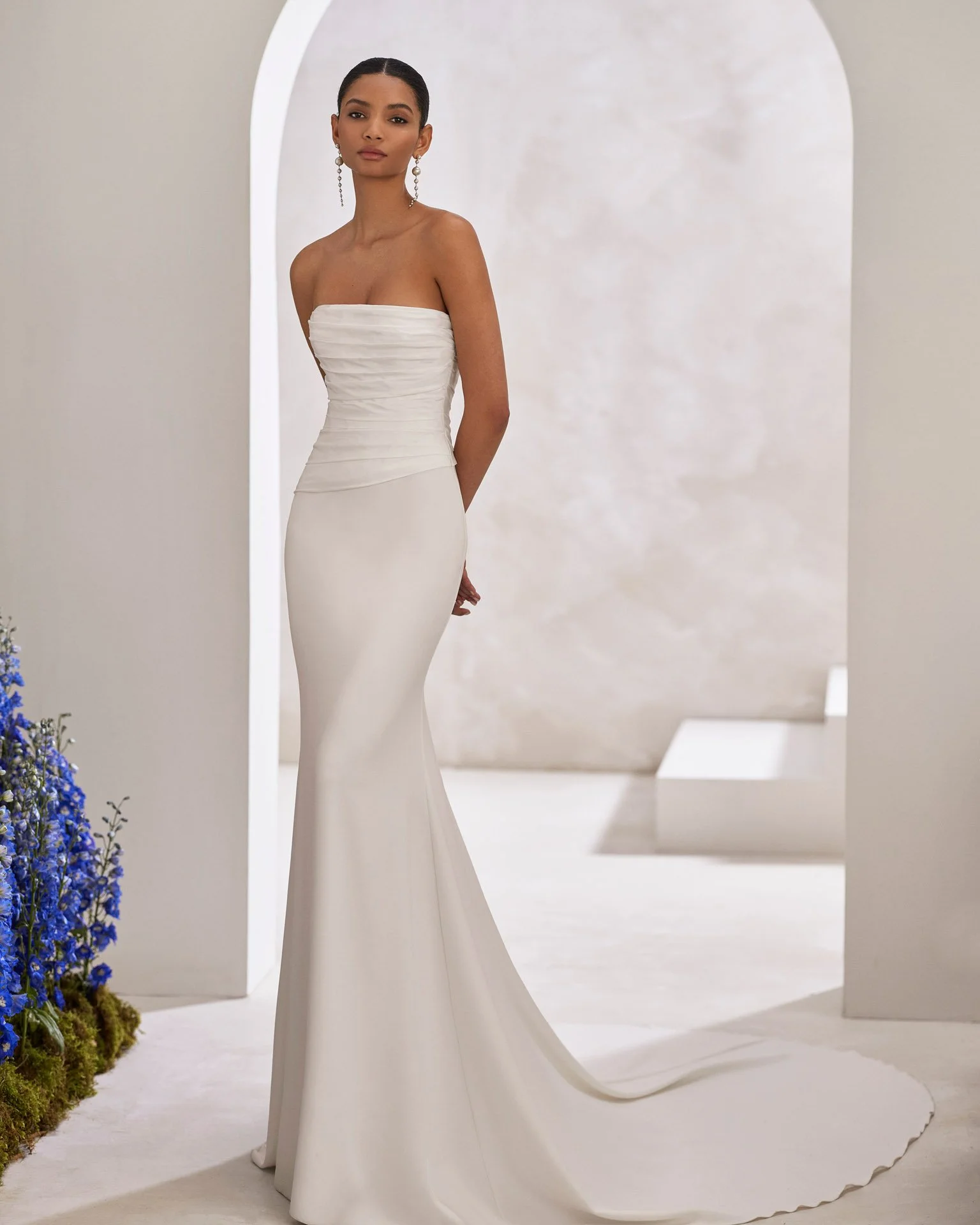 Bride wearing a Taffeta and Crepe Wedding dress by Rosa Clara Couture standing in hallway with archway in background wedding dress at Ashley and Alexandria's Bridal Atelier Birmingham Michigan