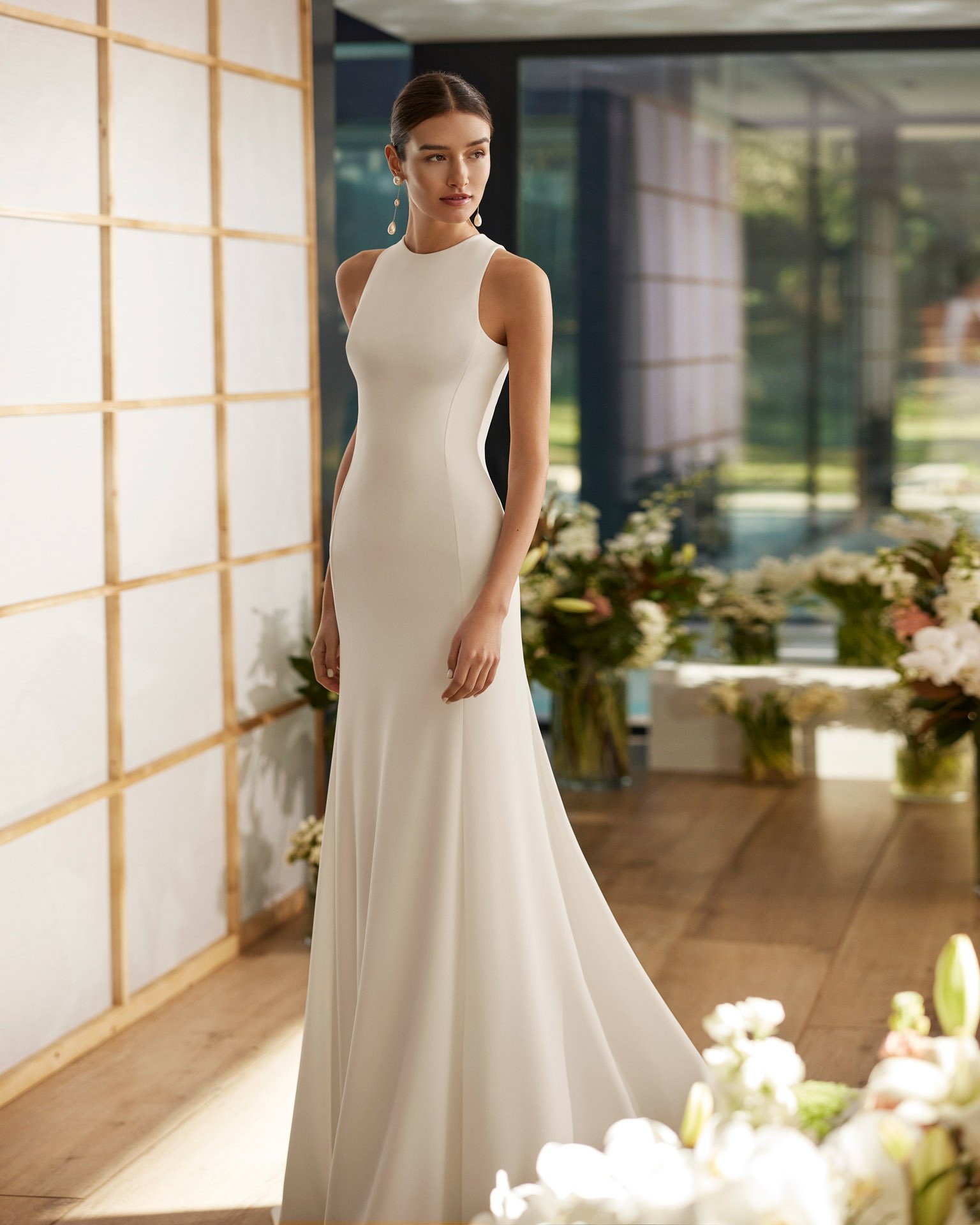 Bride in hallway with floral arrangement in background wearing a Rosa Clara Couture Crepe Sheeth bridal dress Ann Arbor Michigan