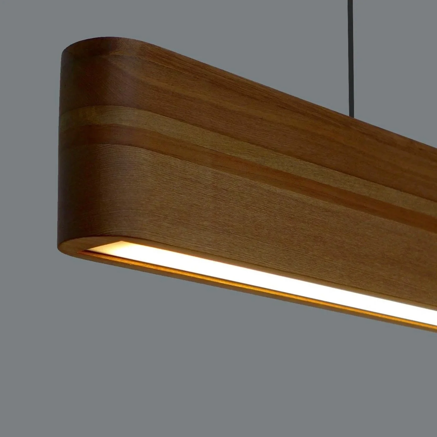 Close-up of a modern wooden ceiling light fixture with an integrated LED light on a gray ceiling.