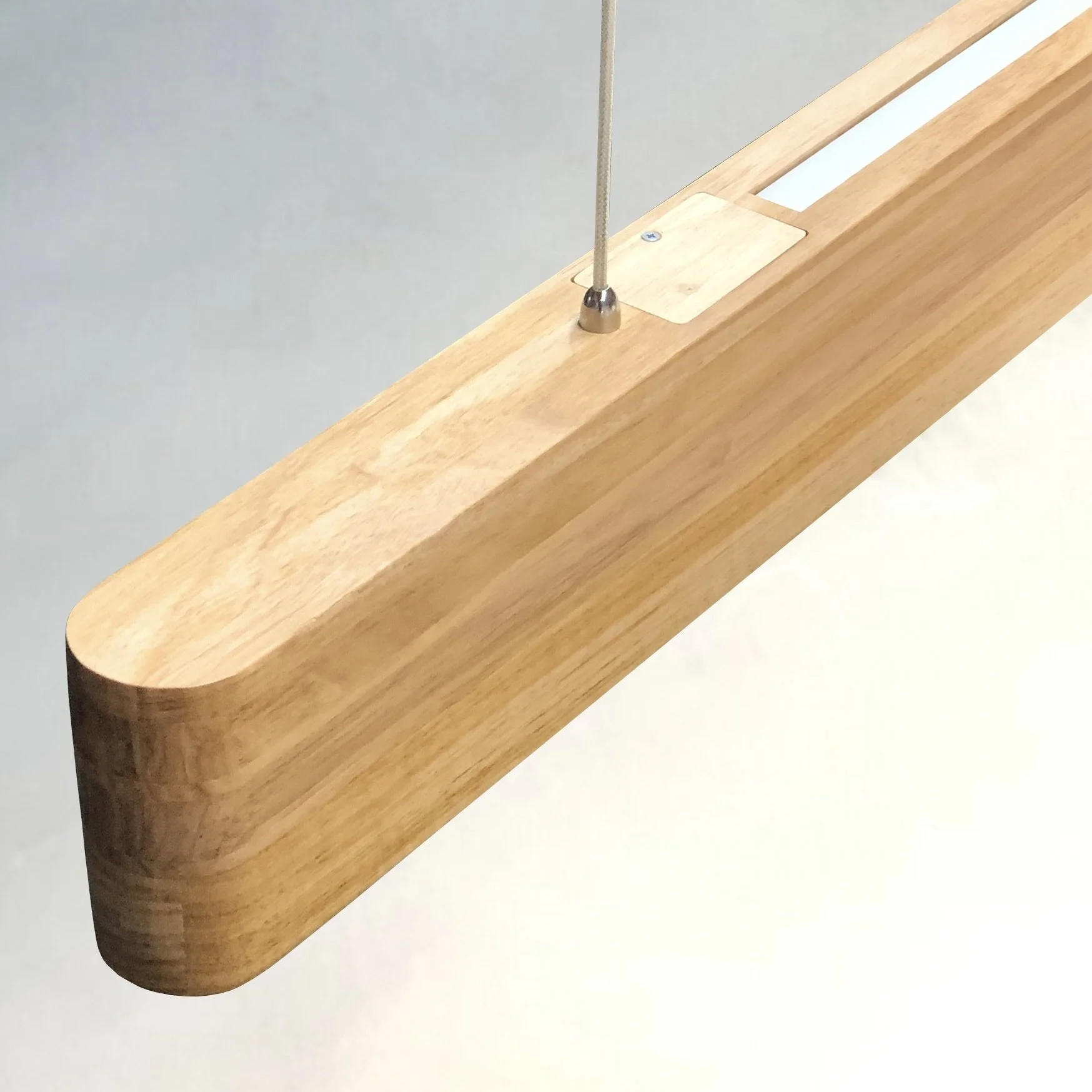 Close-up of a wooden beam with a metal fixture and a cable attached, against a plain background.