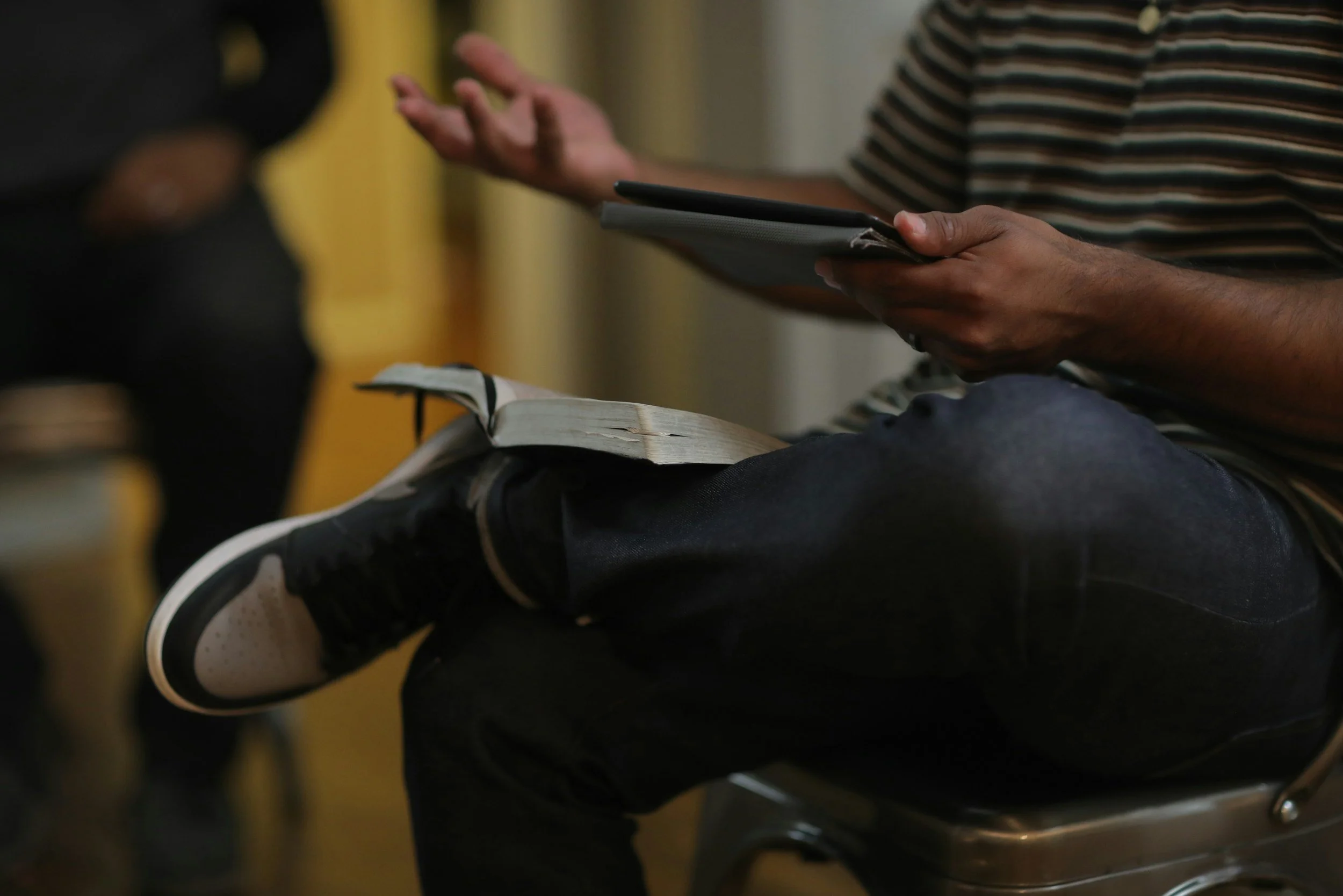 A pastor leads a storywork conversation with congregants with a Bible resting on his calf.