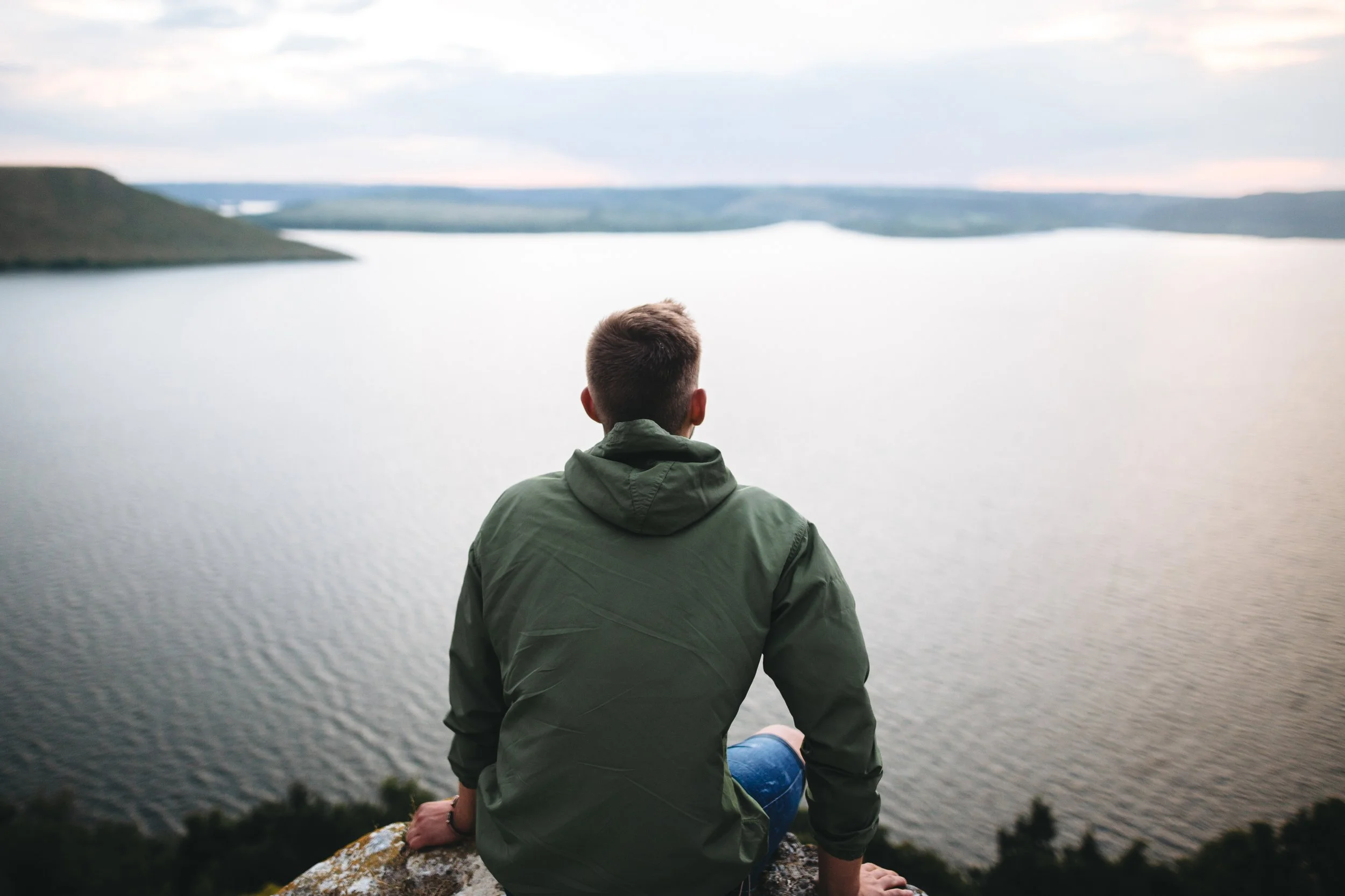 Man looks out at lake contemplating his unwanted sexual behaviors.