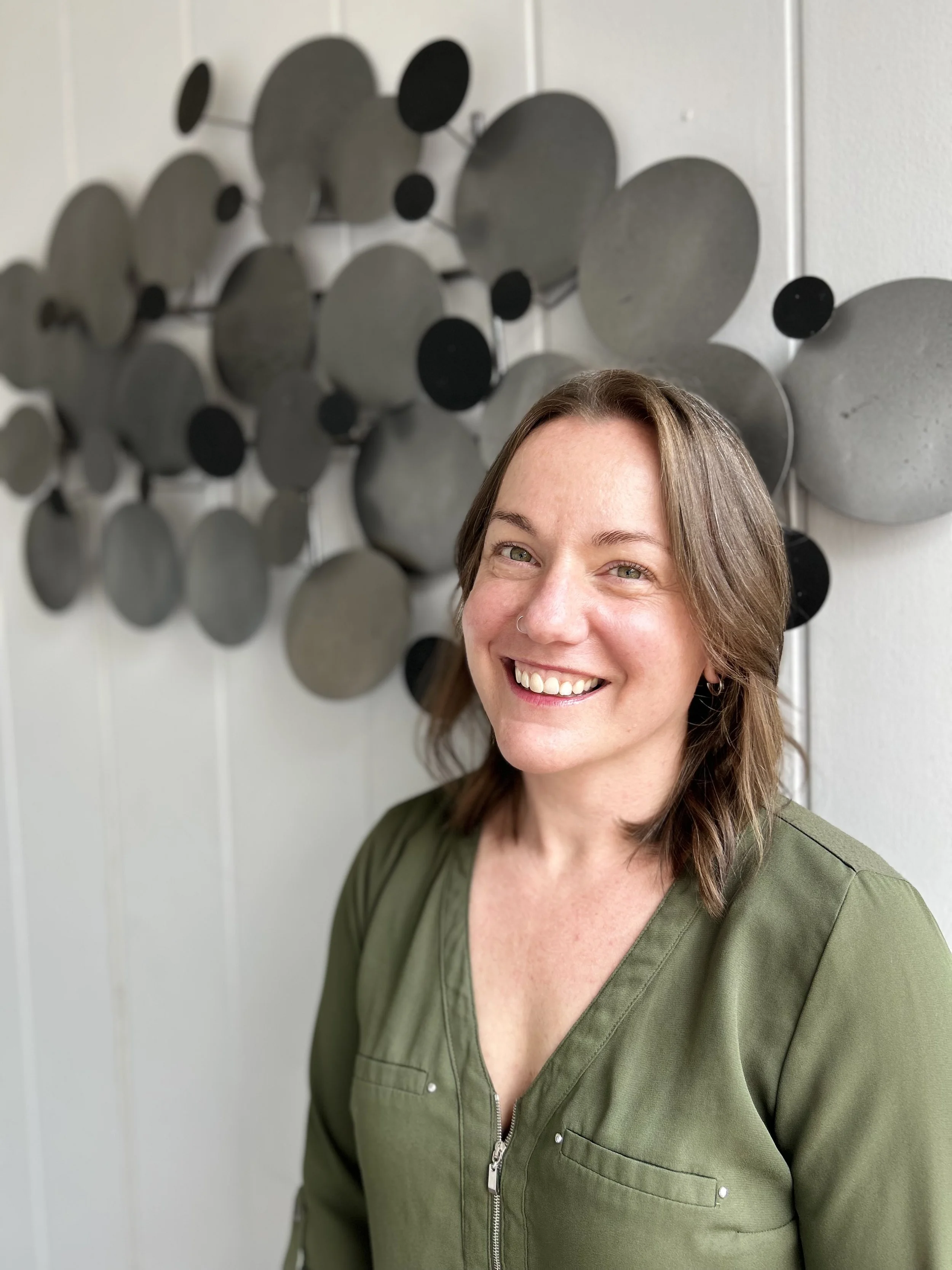 Stephanie Pauline Brooks of Pauline Editing outside in front of a metal piece of art