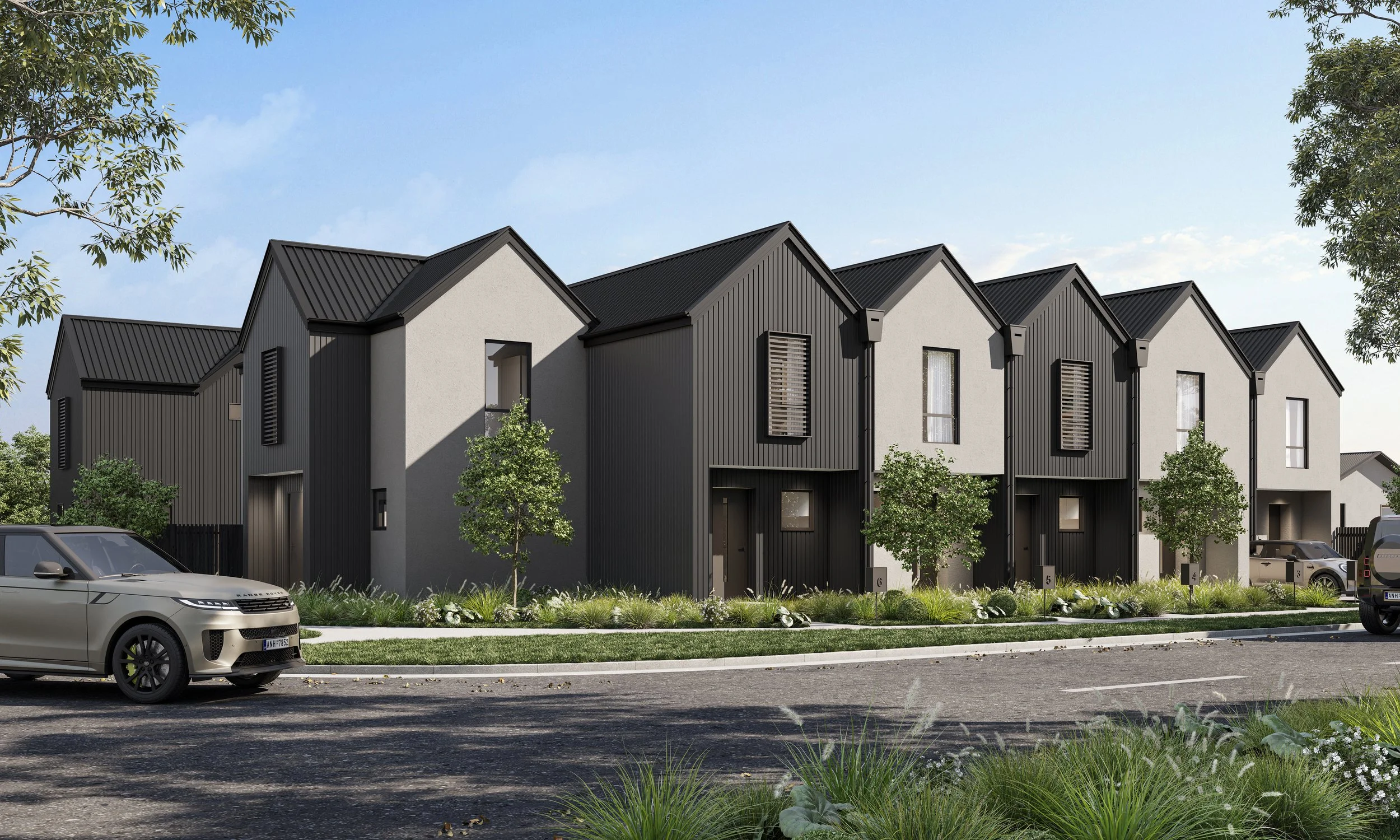 Modern townhouses with black and white exterior, small front yards with trees and plants, cars parked on the street, under a blue sky.