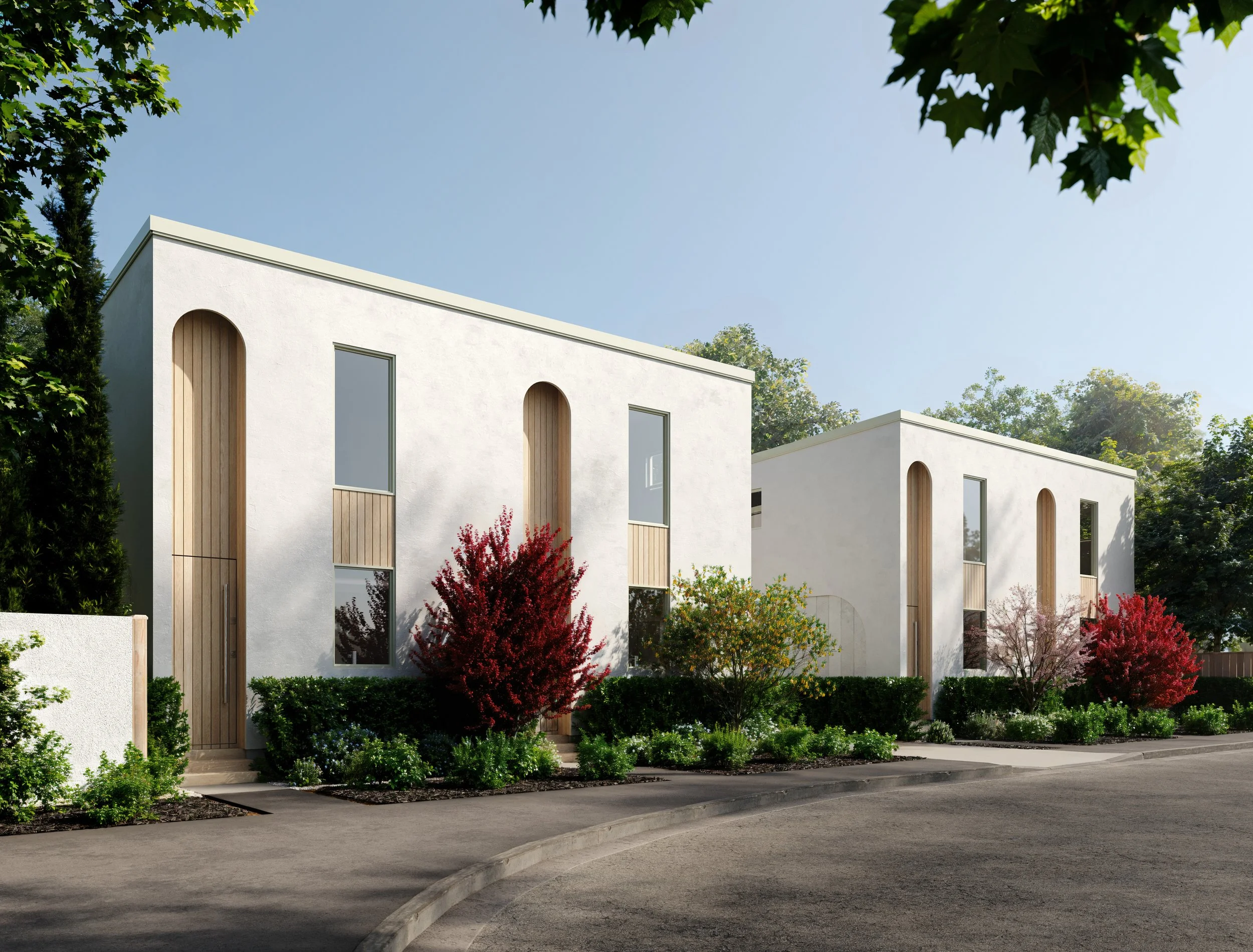 Modern white residential buildings with tall arched windows, wooden accents, surrounded by landscaped greenery and colorful shrubs, under a clear blue sky.