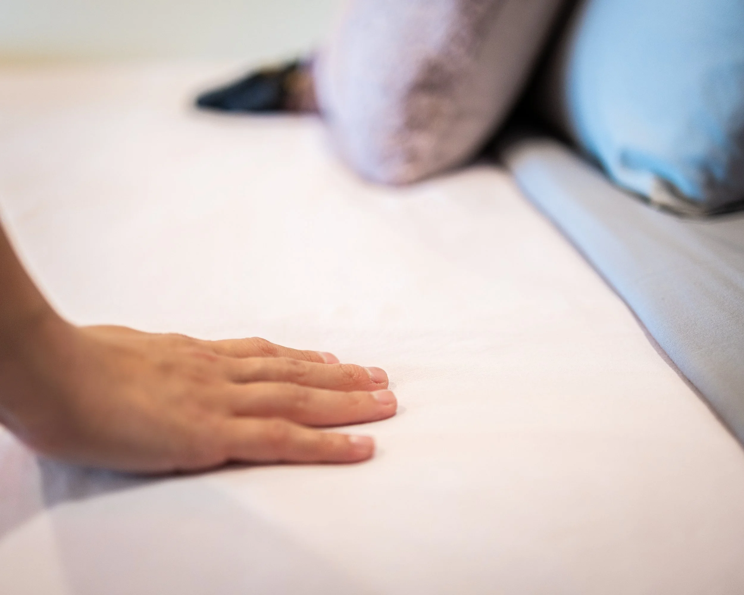 Person pressing a hand on a white surface, with a blurred background of fabric or clothing.