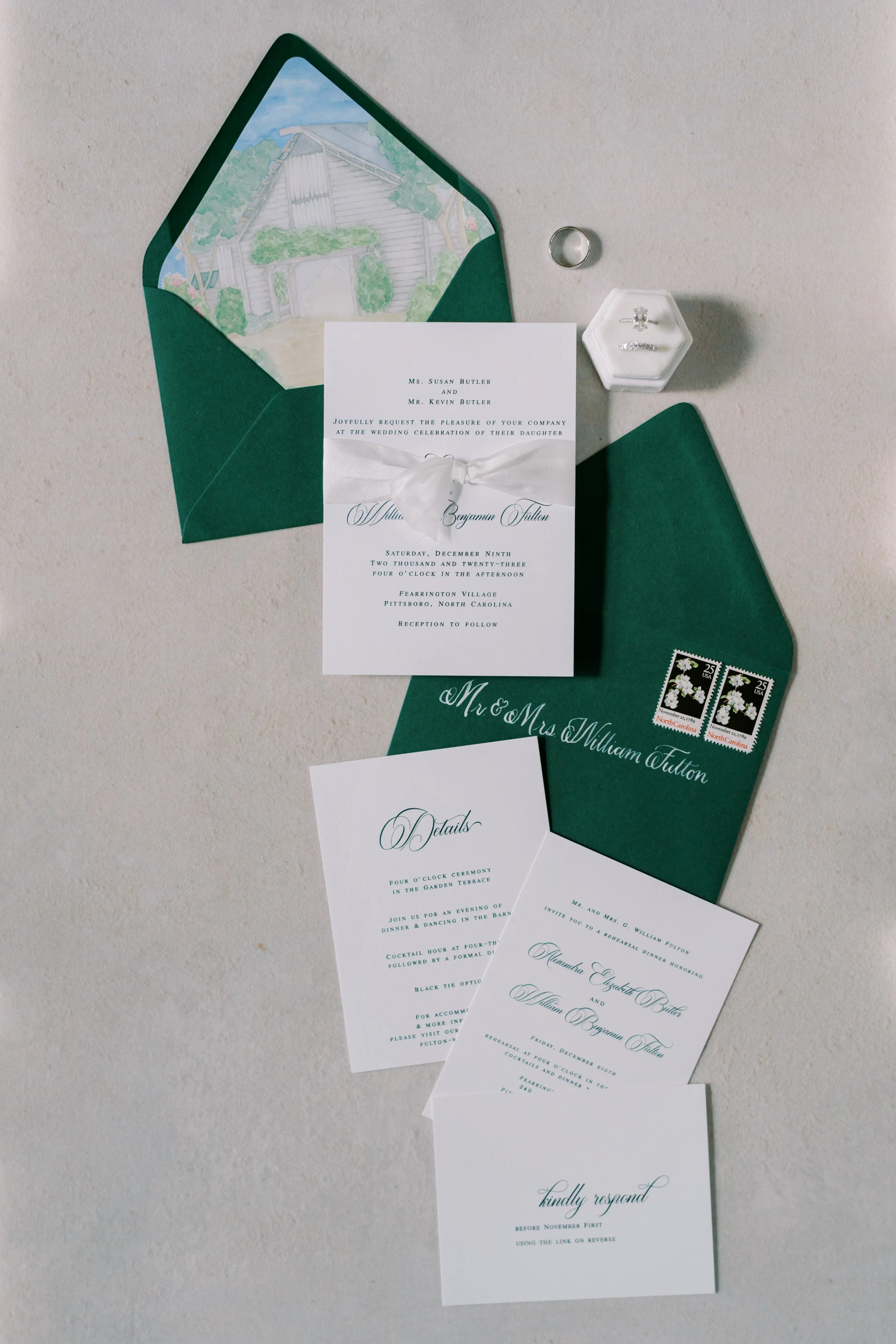 custom wedding invitations with emerald green thermography and blind embossing for Christmas winter wedding. Watercolor venue painting on envelope liner, while silk ribbon, gold wax seal and corresponding details cards