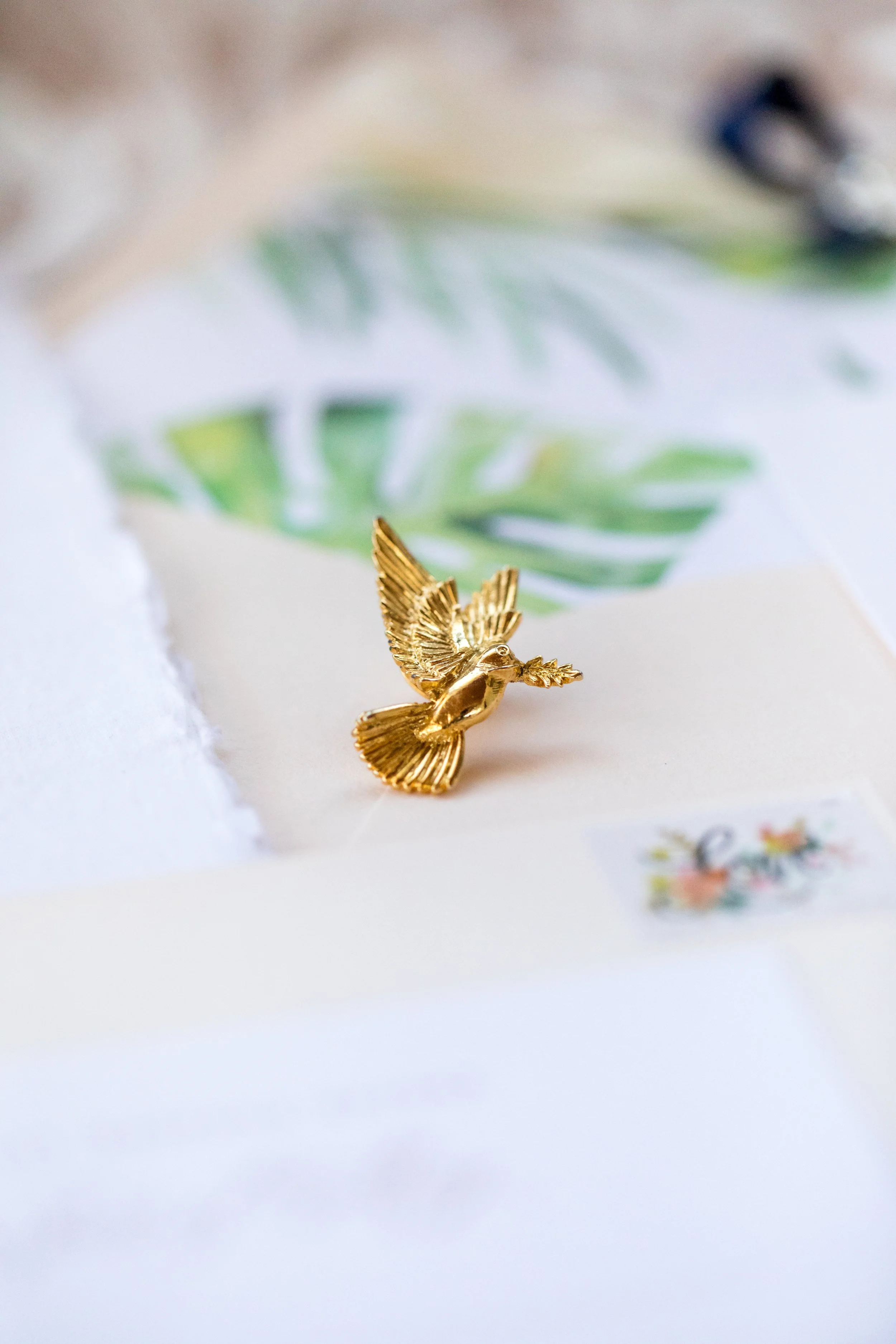 Jacqueline luxury wedding invitation suite featuring pink letterpress, pink silk ribbon, blush envelope with watercolor monstera envelope liner. Handmade paper vow book, velvet pink ring box, monogram garter and pink satin shoes