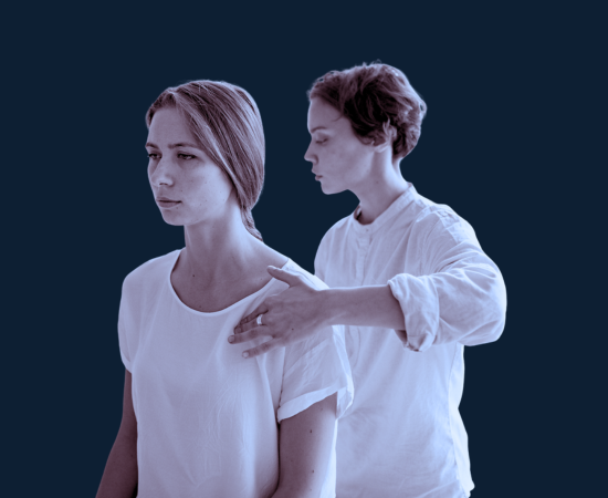 A person standing with eyes closed as another person performs a neck and shoulder massage.