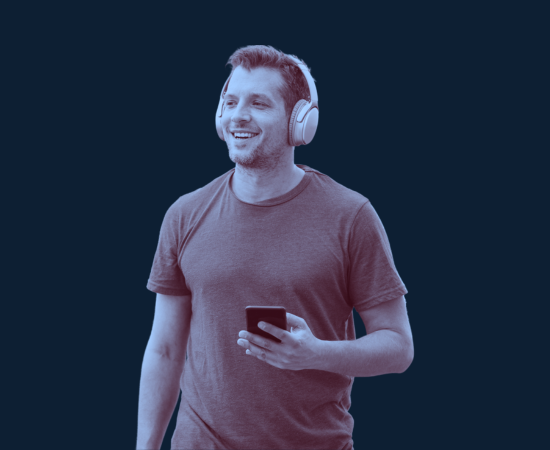 A smiling man wearing headphones and holding a smartphone.