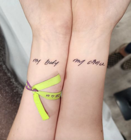 Two wrists with matching tattoos that read "my body" and "my choice".