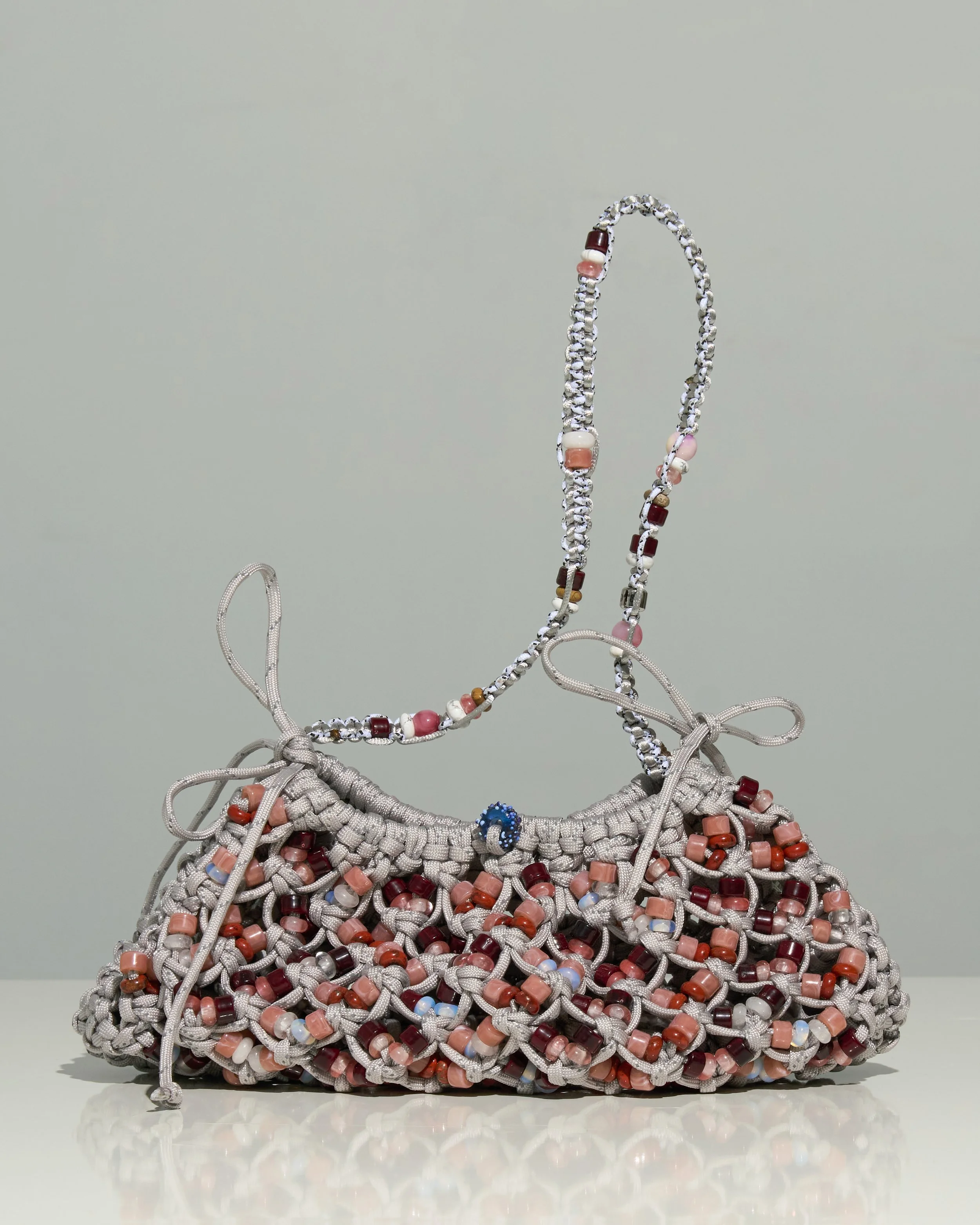 A gray woven handbag with colorful beads and a beaded strap.